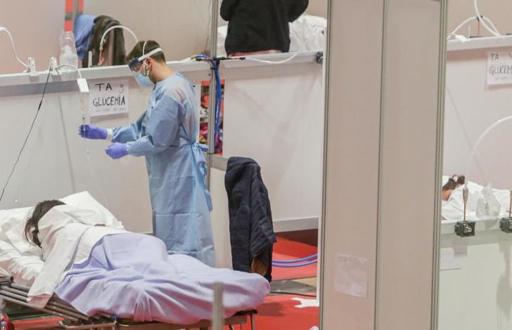 Un profesional sanitario atendiendo a una paciente en el hospital de campaña del Ifema, en Madrid.